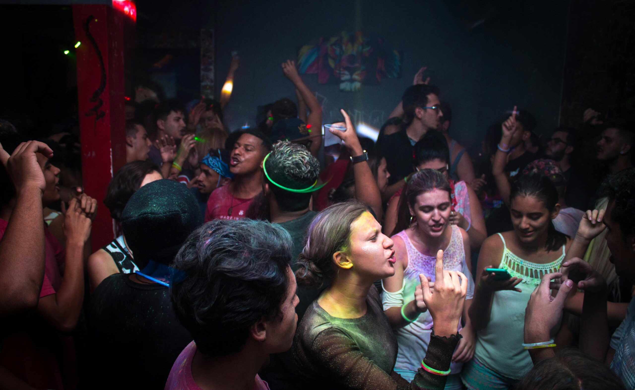 Lively nightclub scene with a vibrant crowd dancing energetically under colorful lights.