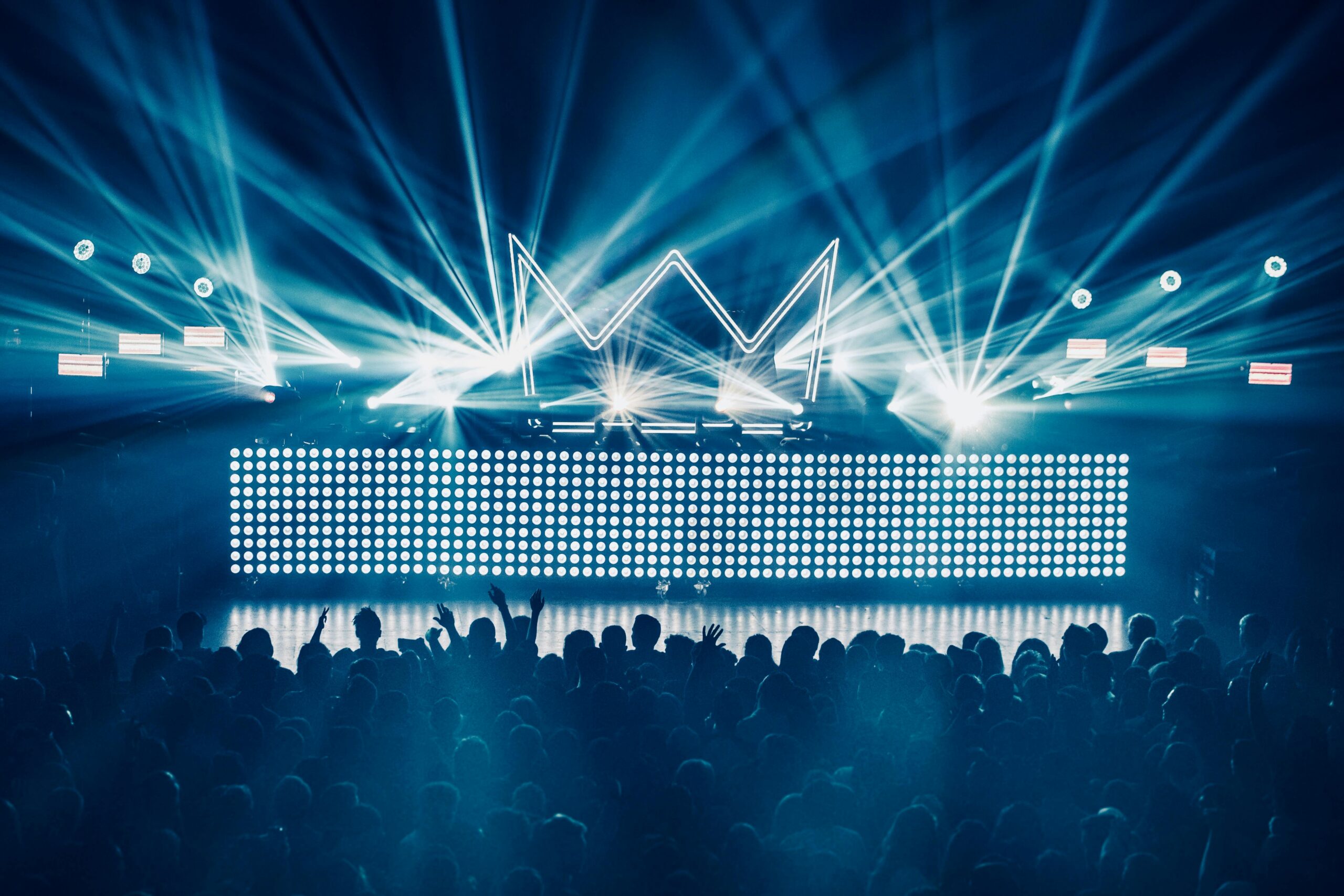 An electrifying concert atmosphere featuring dynamic laser lights and a vibrant crowd enjoying live music.